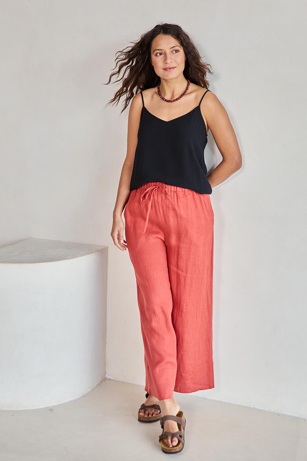 Model Tahneei wearing size 10 of the Linen Cropped Drawstring Pant – Rust in colour Rust, from the front