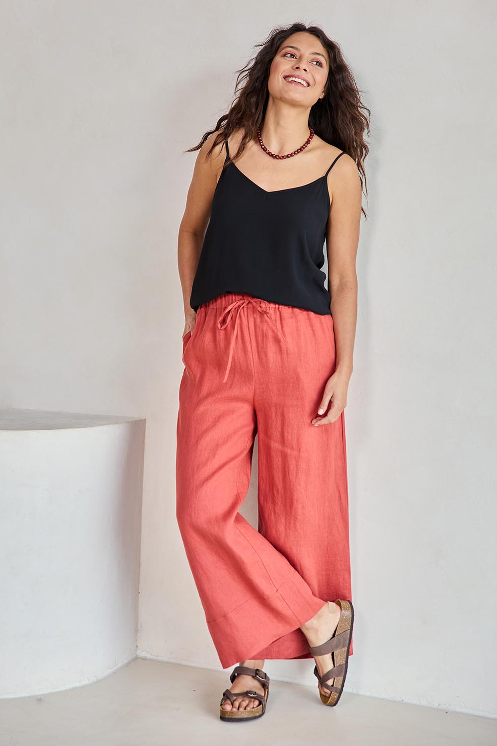 Model Tahneei wearing size 10 of the Linen Cropped Drawstring Pant – Rust in colour Rust, from the front