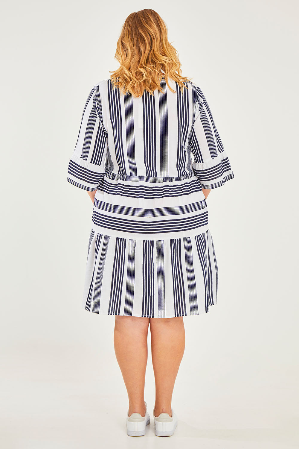 Model Caitlin wearing size 18 of the Maya Button V Neck Layer Dress in colour Navy (Blue), from the back
