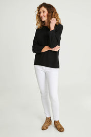 Model Emma wearing size 10 of the Knit Organic Cotton Top Long Sleeve in colour Black (Black), from the front, showing the whole outfit
