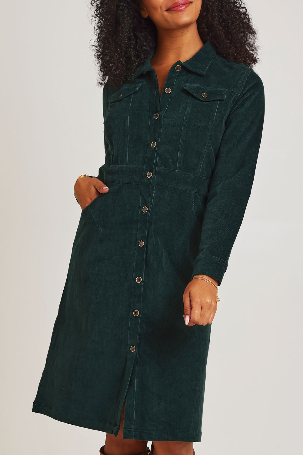 Model Ziara wearing size 10 of the Cotton Corduroy Button Dress in colour Pine (Green), from the front, cropped image
