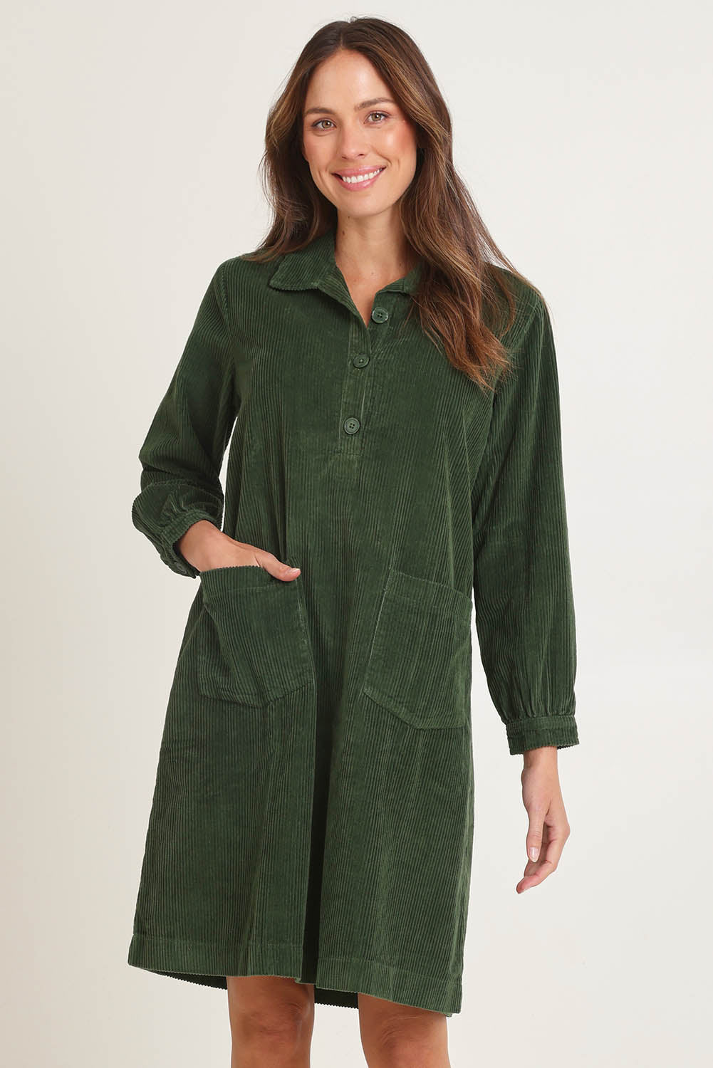 Model Madeline wearing size 10 of the Cord Solids Pockets Dress in colour Military (Green), from the front, cropped image