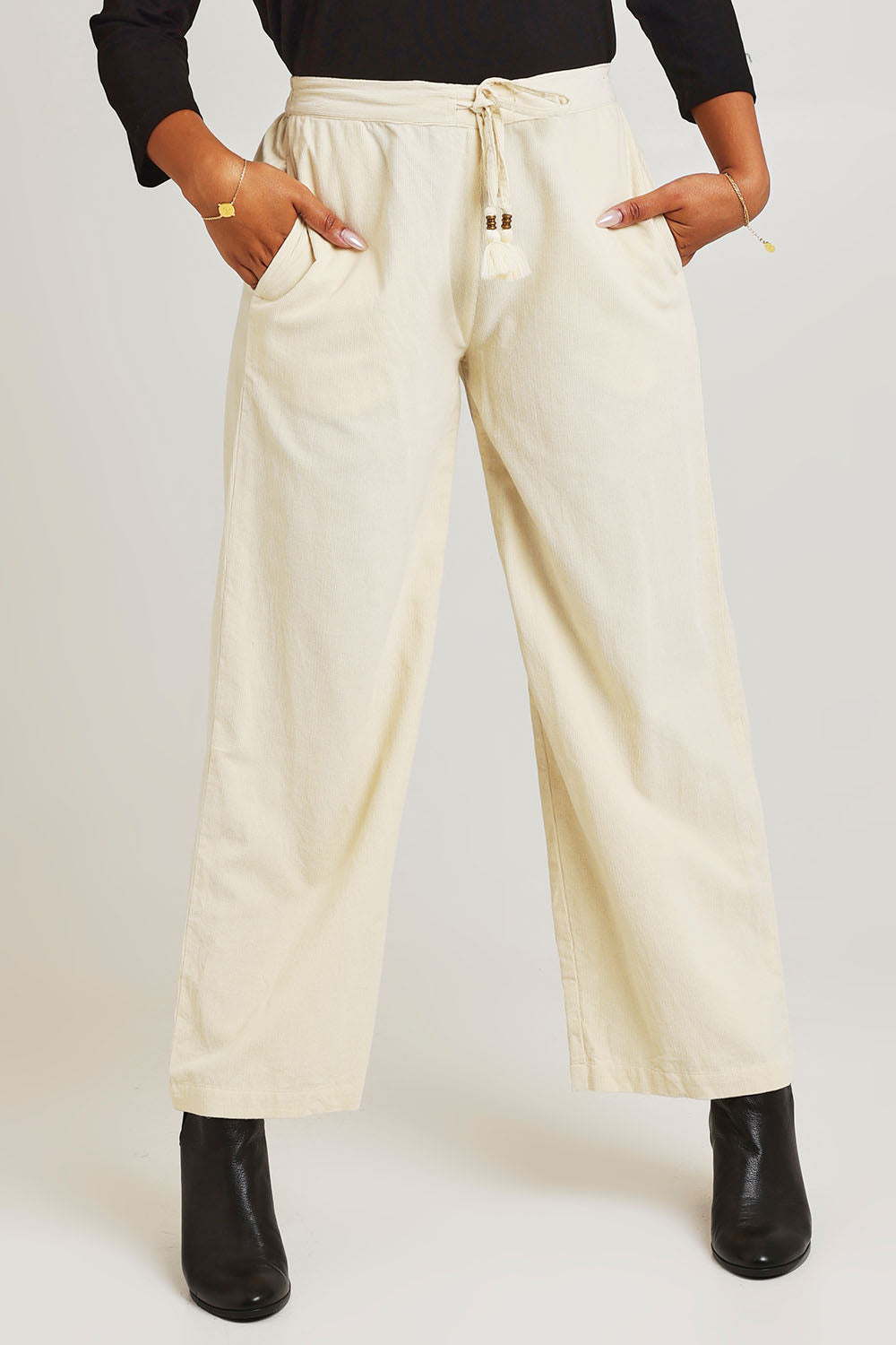 Model Ziara wearing size 10 of the Corduroy Flared Trouser in colour Ecru, from the front, cropped image