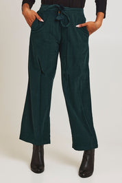 Model Ziara wearing size 10 of the Corduroy Flared Trouser in colour Pine (Green), from the front, cropped image