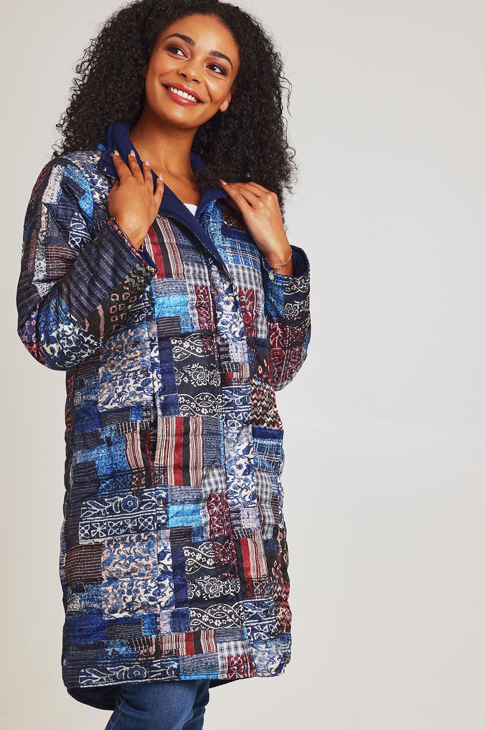 Model Ziara wearing size 10 of the Kantha Reversible Patch Puffer Coat in colour Kantha (Blue), from the front, cropped image