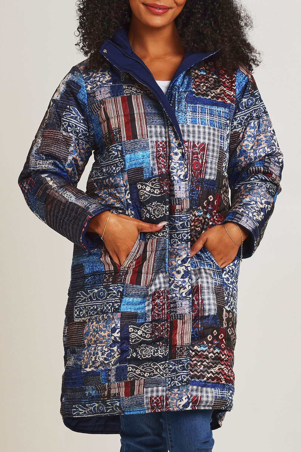Model Ziara wearing size 10 of the Kantha Reversible Patch Puffer Coat in colour Kantha (Blue), from the front, cropped image