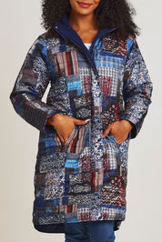 Model Ziara wearing size 10 of the Kantha Reversible Patch Puffer Coat in colour Kantha (Blue), from the front, cropped image