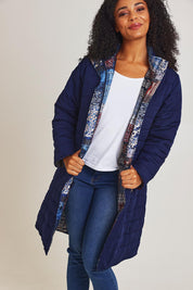 Model Ziara wearing size 10 of the Kantha Reversible Patch Puffer Coat in colour Kantha (Blue), from the front, cropped image