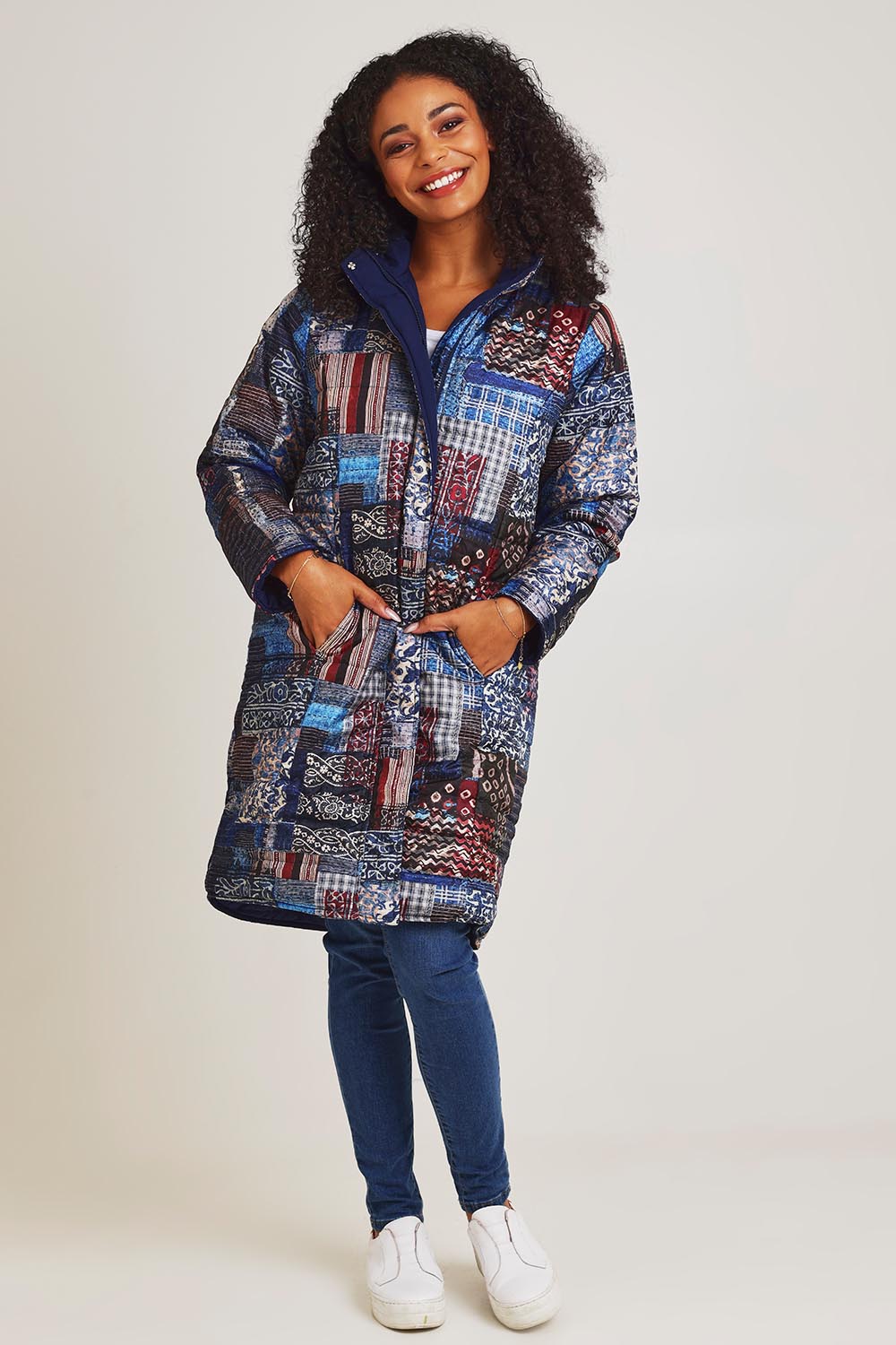 Model Ziara wearing size 10 of the Kantha Reversible Patch Puffer Coat in colour Kantha (Blue), from the front, showing the whole outfit