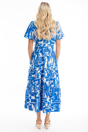 A model wearing the Cannes Ruched Waist Dress in colour Print (Blue), from the back