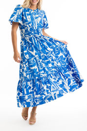 A model wearing the Cannes Ruched Waist Dress in colour Print (Blue), from the front, cropped image
