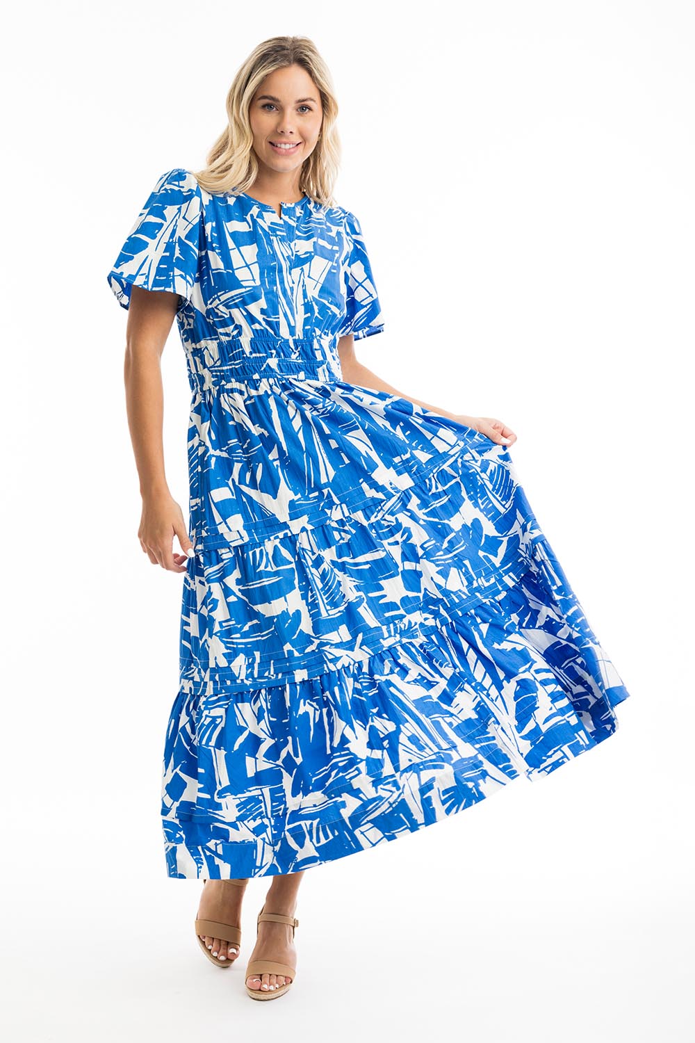 A model wearing the Cannes Ruched Waist Dress in colour Print (Blue), from the front, showing the whole outfit