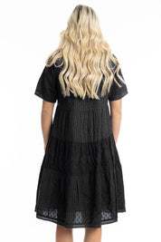 A model wearing the Essential Broderie Layers Cotton Dress in colour Black (Black), from the back