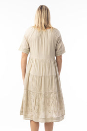 A model wearing the Essential Broderie Layers Cotton Dress in colour Sand, from the back
