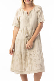 A model wearing the Essential Broderie Layers Cotton Dress in colour Sand, from the front, cropped image