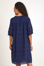 Model Pamelar wearing size 10 of the Essentials Pleated Cotton Dress - Navy in colour Navy, from the back