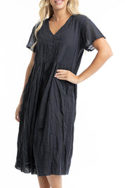 A model wearing the Essentials Organic Cotton Gauze Peak Dress in colour Black (Black), from the front, cropped image