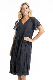 A model wearing the Essentials Organic Cotton Gauze Peak Dress in colour Black (Black), from the front, cropped image