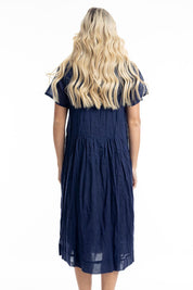 A model wearing the Essentials Organic Cotton Gauze Peak Dress in colour Navy (Blue), from the back