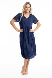 A model wearing the Essentials Organic Cotton Gauze Peak Dress in colour Navy (Blue), from the front, showing the whole outfit