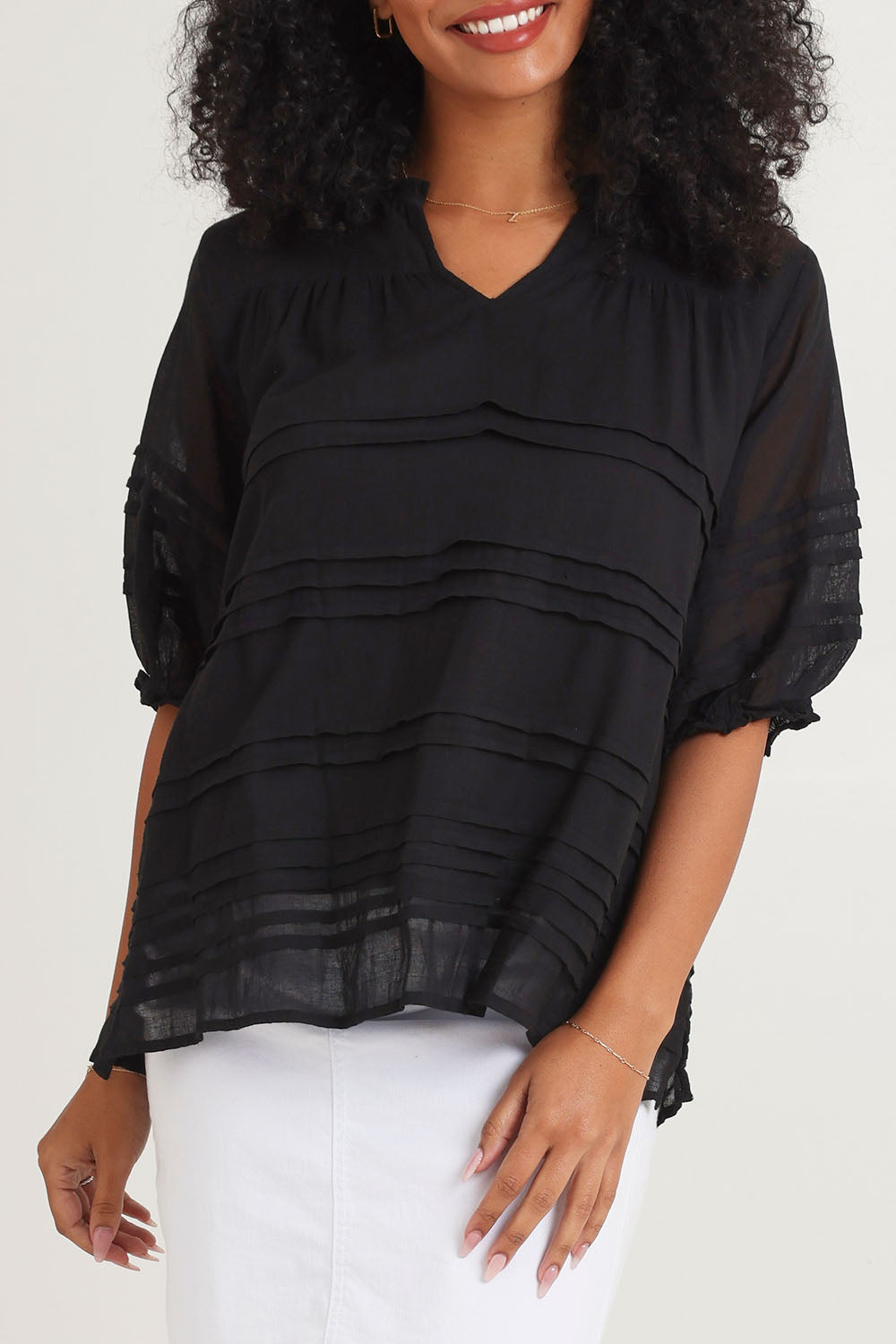 Model Ziara wearing size 10 of the Essentials Organic Cotton Pleated Top in colour Black (Black), from the front, cropped image