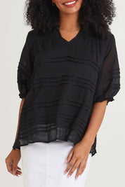Model Ziara wearing size 10 of the Essentials Organic Cotton Pleated Top in colour Black (Black), from the front, cropped image