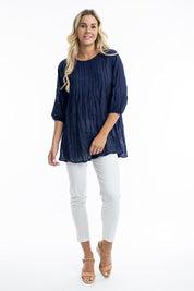 A model wearing the Essentials Organic Cotton Gauze Long Pleated Top in colour Navy (Blue), from the front, showing the whole outfit