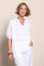 Model Riinar wearing size 10 of the Essentials Pleated Cotton Top - White in colour White, from an angle