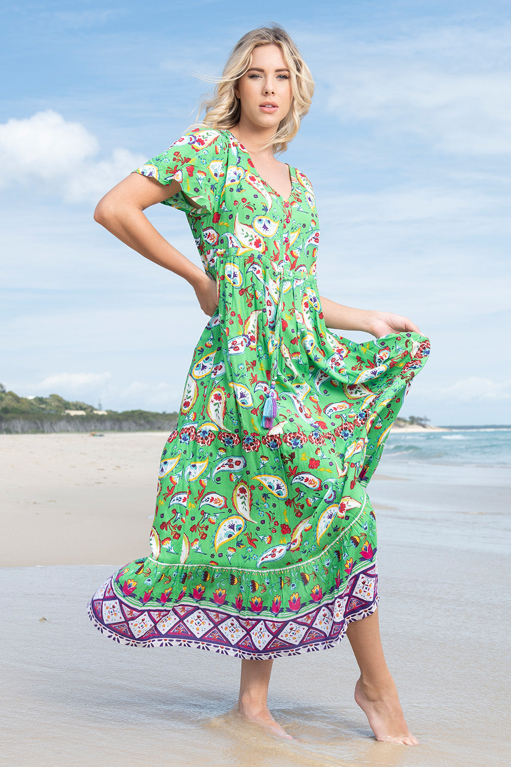 A model wearing the Famagusta Cap Sleeve Layers Dress in colour Green (Green), from the front, showing the whole outfit