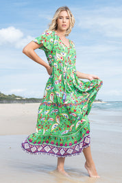 A model wearing the Famagusta Cap Sleeve Layers Dress in colour Green (Green), from the front, showing the whole outfit