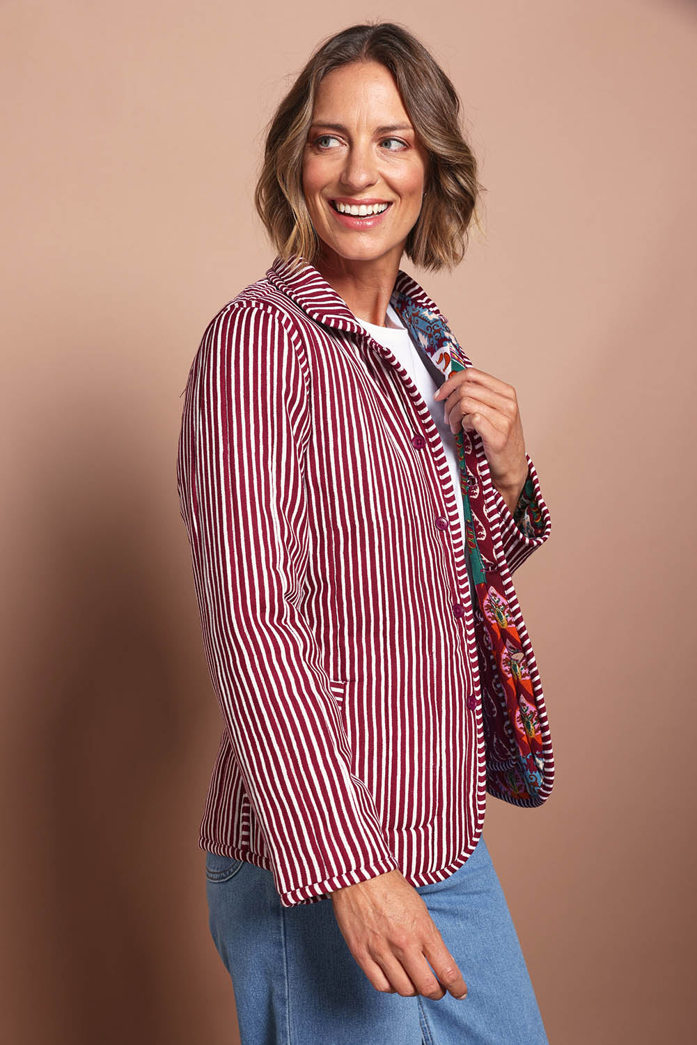 Model Riina wearing size 10 of the Reversible Jacket in colour Prato (Red), from the front, cropped image