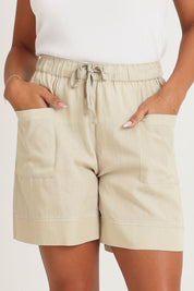 Model Ziara wearing size 10 of the Essentials Linen Blend Shorts in colour Sand, from the front, cropped image