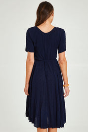 Model Madeline wearing size 10 of the Essentials Godet Short Sleeve Dress in colour Navy (Blue), from the back