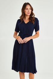 Model Madeline wearing size 10 of the Essentials Godet Short Sleeve Dress in colour Navy (Blue), from the front, cropped image