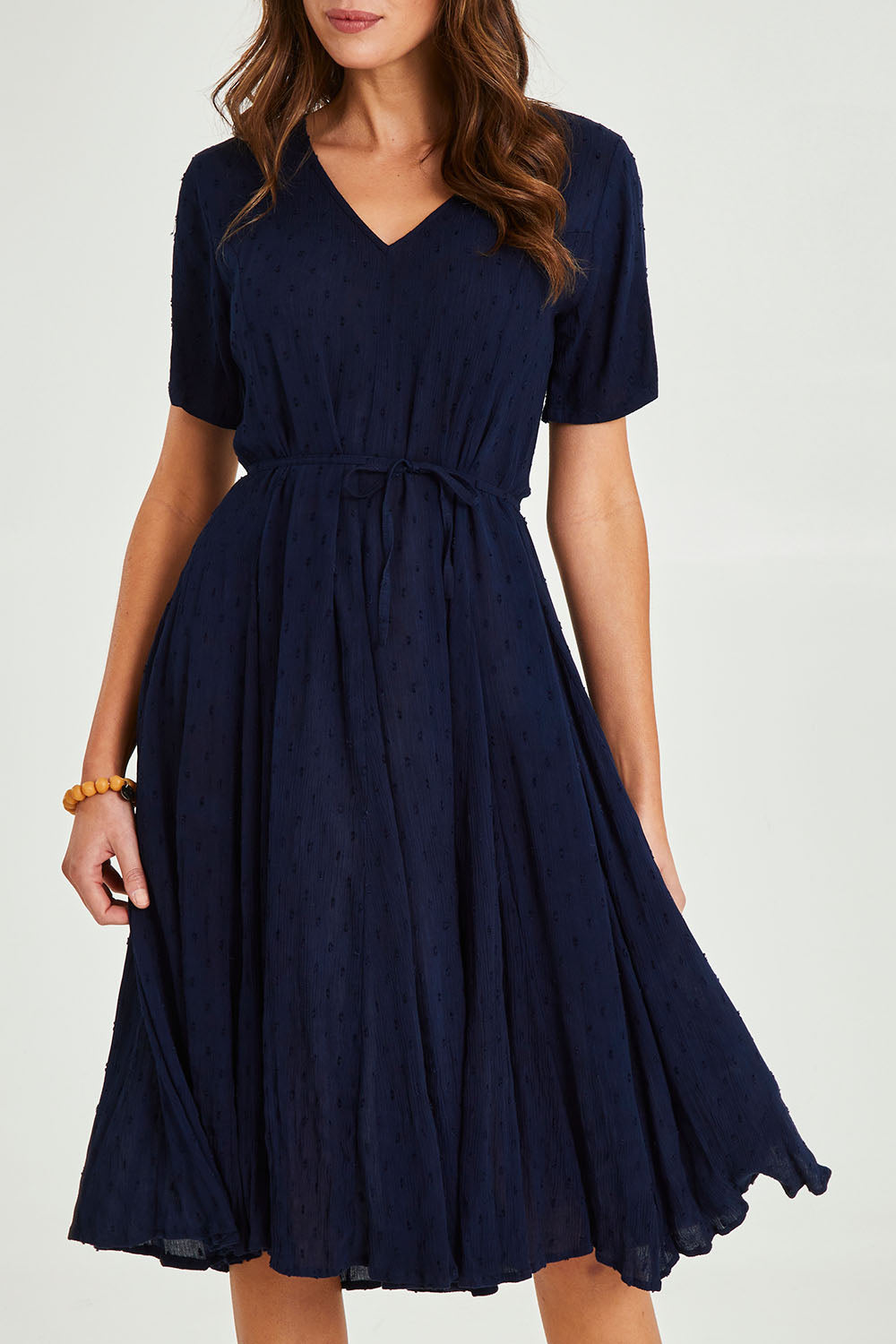 Model Madeline wearing size 10 of the Essentials Godet Short Sleeve Dress in colour Navy (Blue), from the front, cropped image