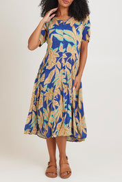 Model Ziara wearing size 10 of the Short Sleeve Godet Dress in colour Blue, from the front, cropped image