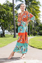 A model wearing the Serengetti V Neckline Dress in colour Red (Green), from the front, showing the whole outfit