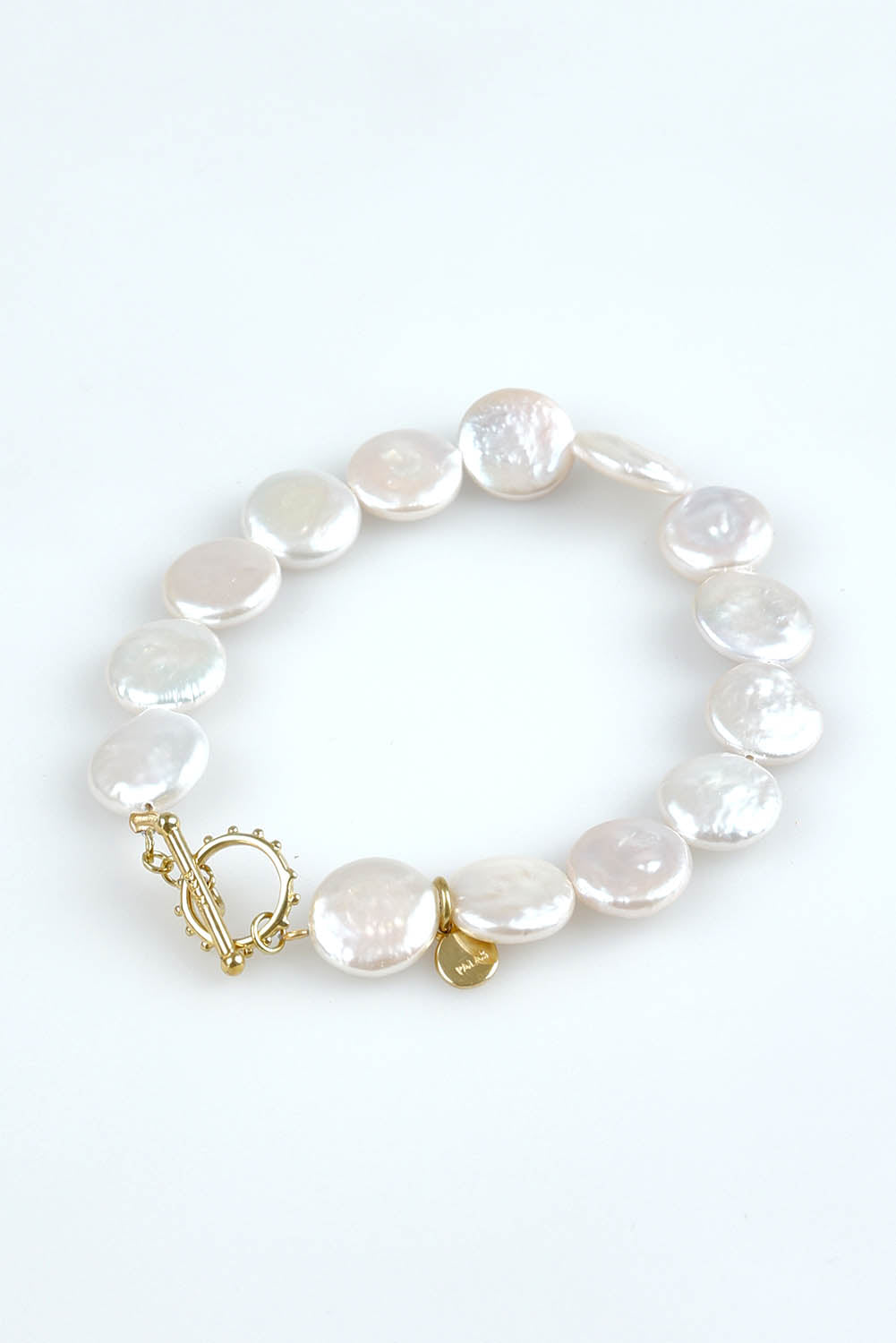 A model wearing the Pearl Fob Bracelet in colour Pearl (White), from the front, showing the whole outfit