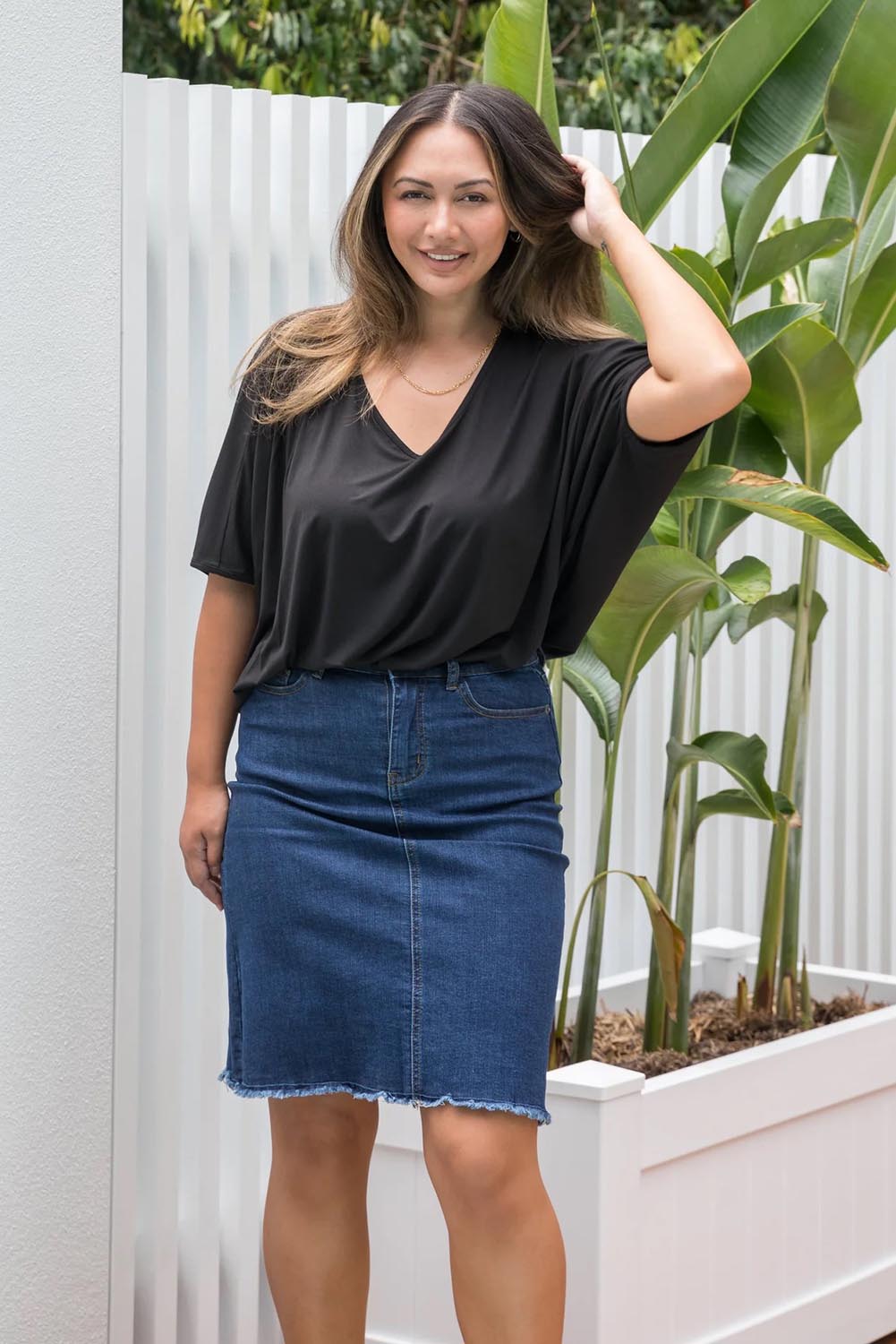 A model wearing the Frayed Denim Skirt in colour DarkDenim (Blue), from the front, showing the whole outfit