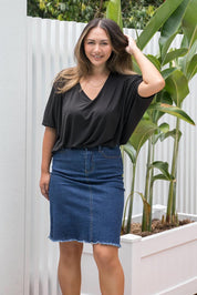 A model wearing the Frayed Denim Skirt in colour DarkDenim (Blue), from the front, showing the whole outfit