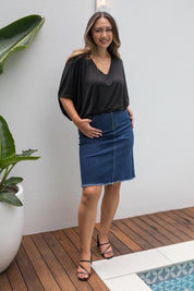 A model wearing the Frayed Denim Skirt in colour DarkDenim (Blue), from the front, showing the whole outfit