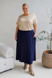 A model wearing the Adeline Bamboo Skirt in colour Navy (Blue), from the front, showing the whole outfit