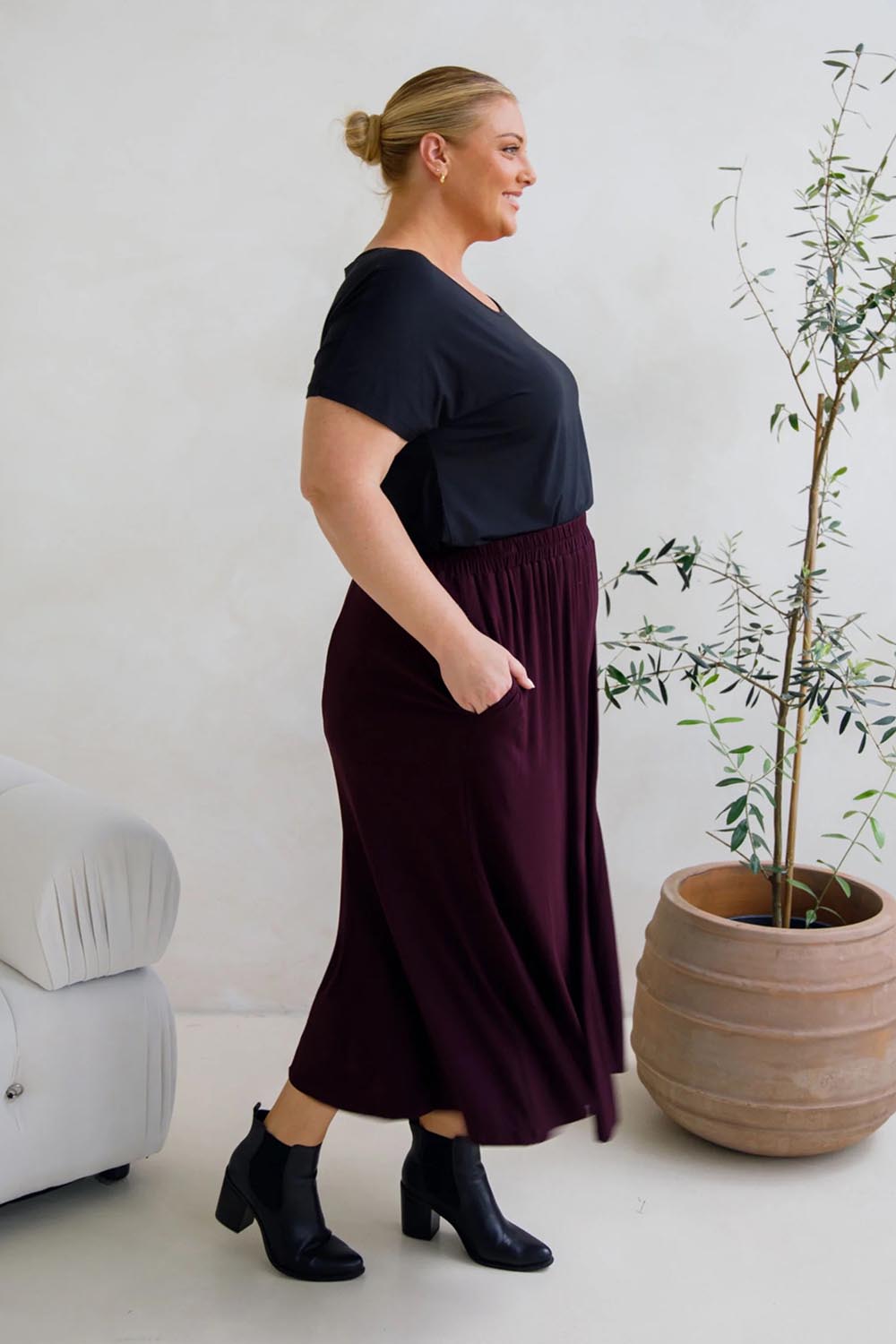 A model wearing the Adeline Bamboo Skirt in colour Shiraz (Purple), from the front, showing the whole outfit