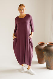 A model wearing the Alviva Lounge Dress in colour Shiraz (Purple), from the front, showing the whole outfit