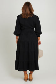 Model Monique wearing size L of the L/S Ruffle Wrap Dress in colour Black (Black), from the back