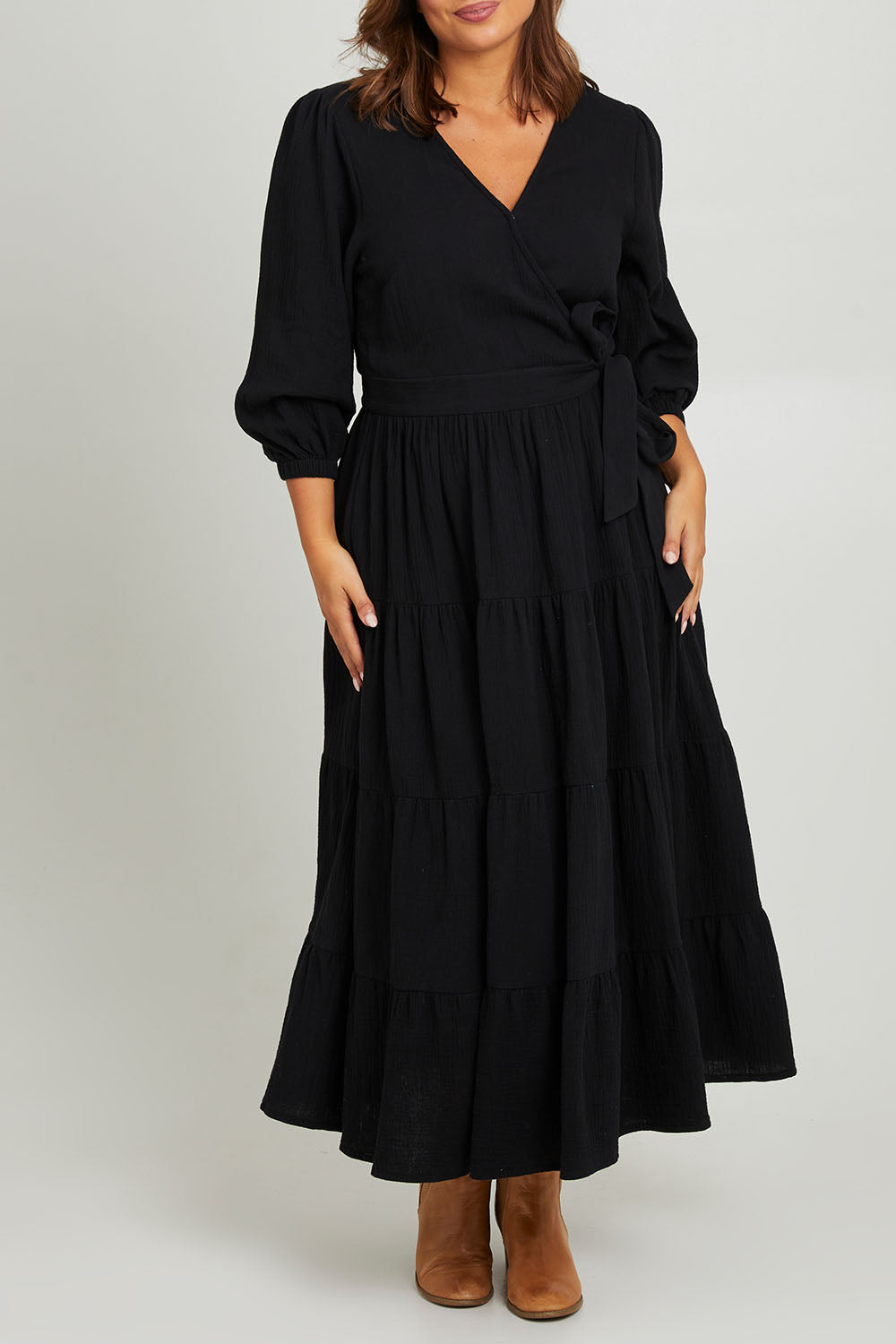Model Monique wearing size L of the L/S Ruffle Wrap Dress in colour Black (Black), from the front, cropped image
