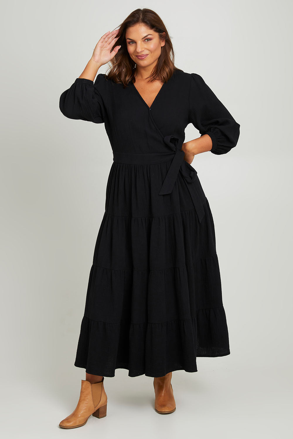 Model Monique wearing size L of the L/S Ruffle Wrap Dress in colour Black (Black), from the front, showing the whole outfit