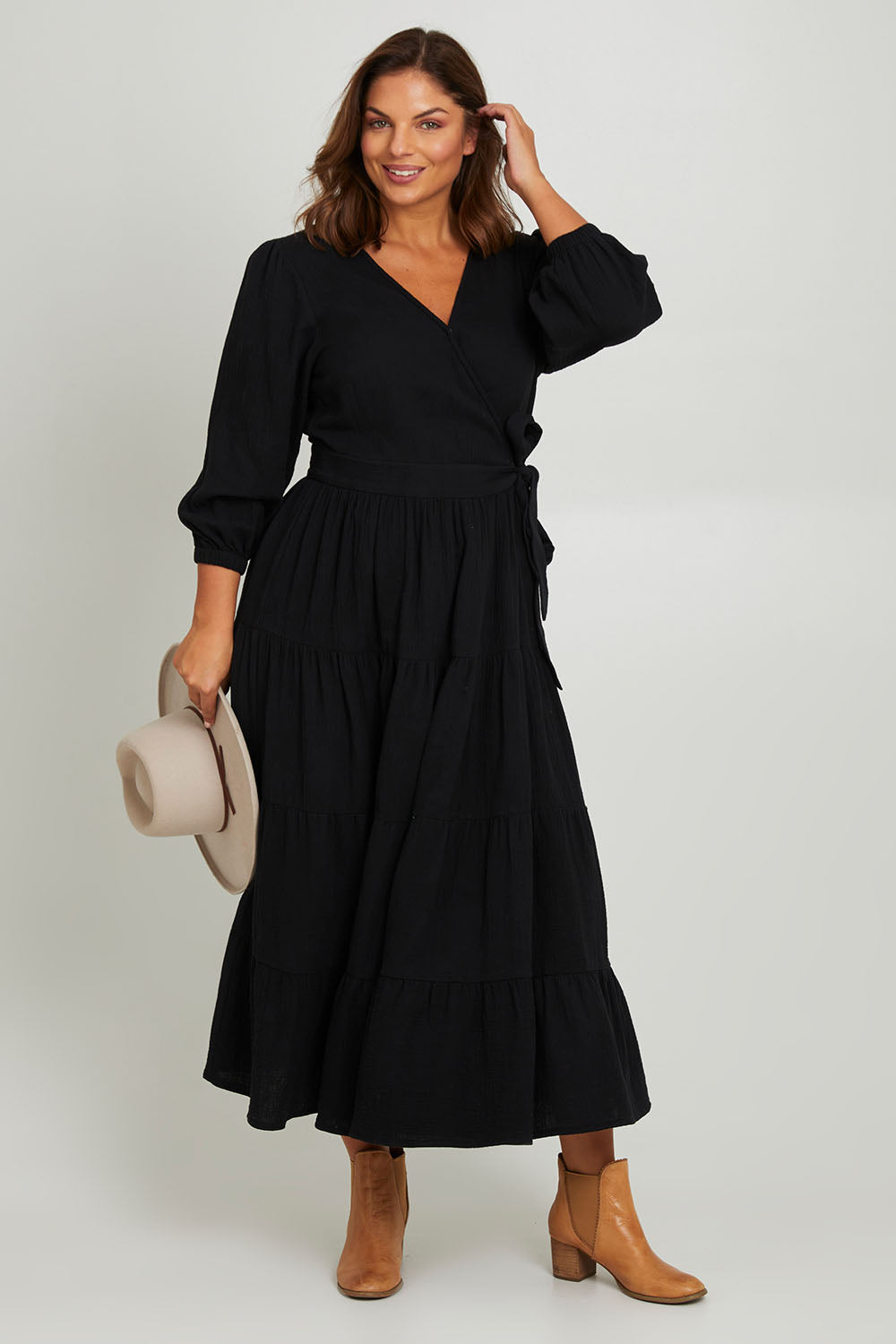 Model Monique wearing size L of the L/S Ruffle Wrap Dress in colour Black (Black), from the front, showing the whole outfit