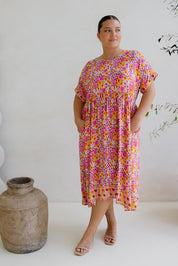 A model wearing the Frolic Dress in colour Harmony, from the front, showing the whole outfit