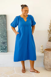 A model wearing the Novella Cotton Dress in colour Ultramarin (Blue), from the front, showing the whole outfit